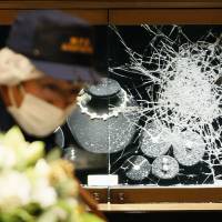 A police officer examines the Harry Winston jewelry salon in Omotesando Hills in central Tokyo on the night of Nov. 20, 2015. | KYODO
