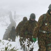 Ground Self-Defense Force personnel traverse through snow as they search for four missing people on Mount Asahidake in Hokkaido on Wednesday afternoon, before they were found alive later in the day. | KYODO