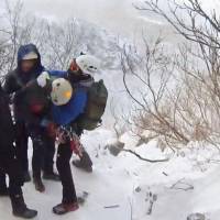 A climber (second from right) who went missing earlier this week on Mount Asahidake in Hokkaido is rescued by police Thursday morning. | HOKKAIDO PREFECTURAL POLICE / VIA KYODO