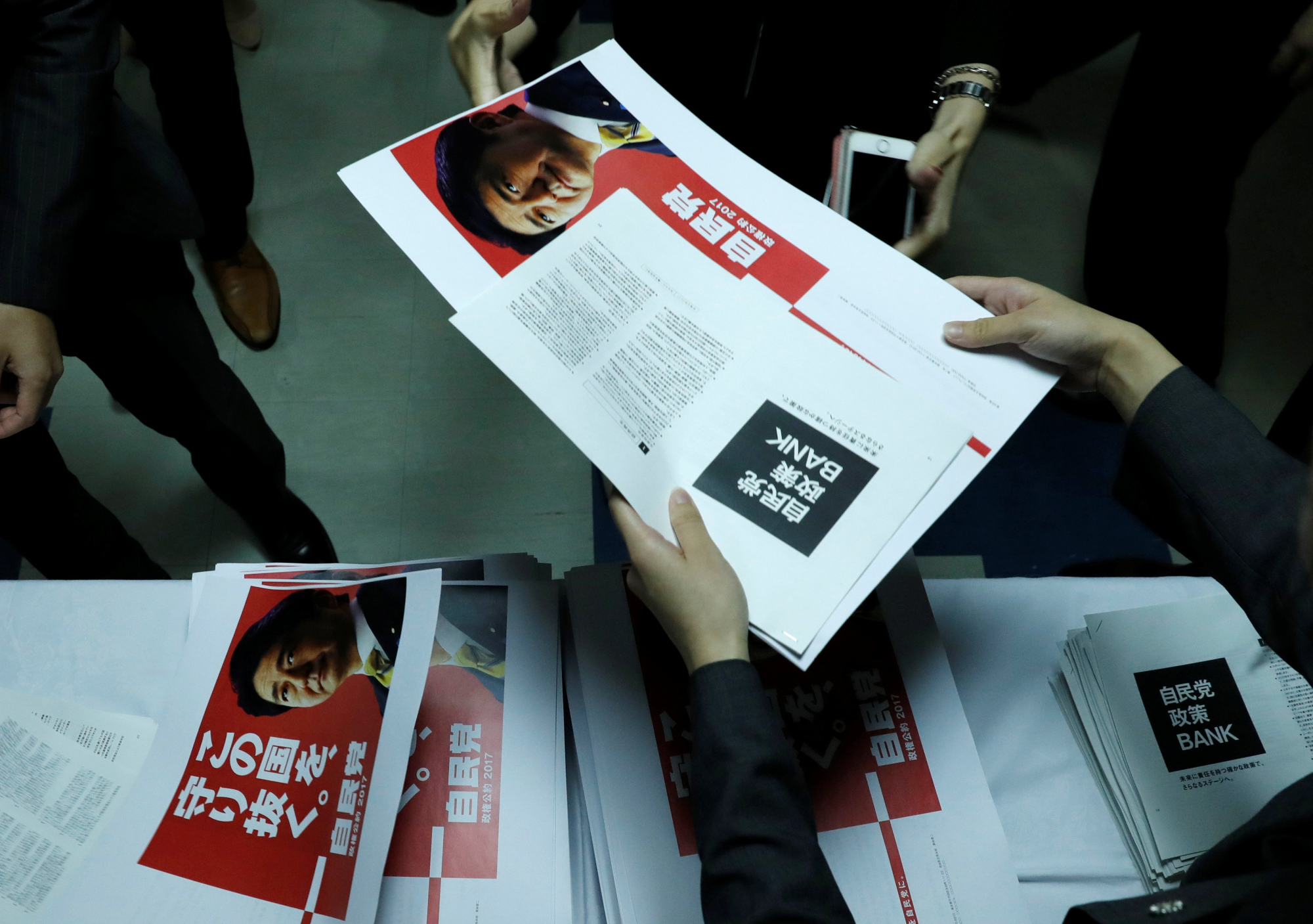 Reporters are given campaign leaflets for the Liberal Democratic Party at its Tokyo headquarters on Monday. | REUTERS