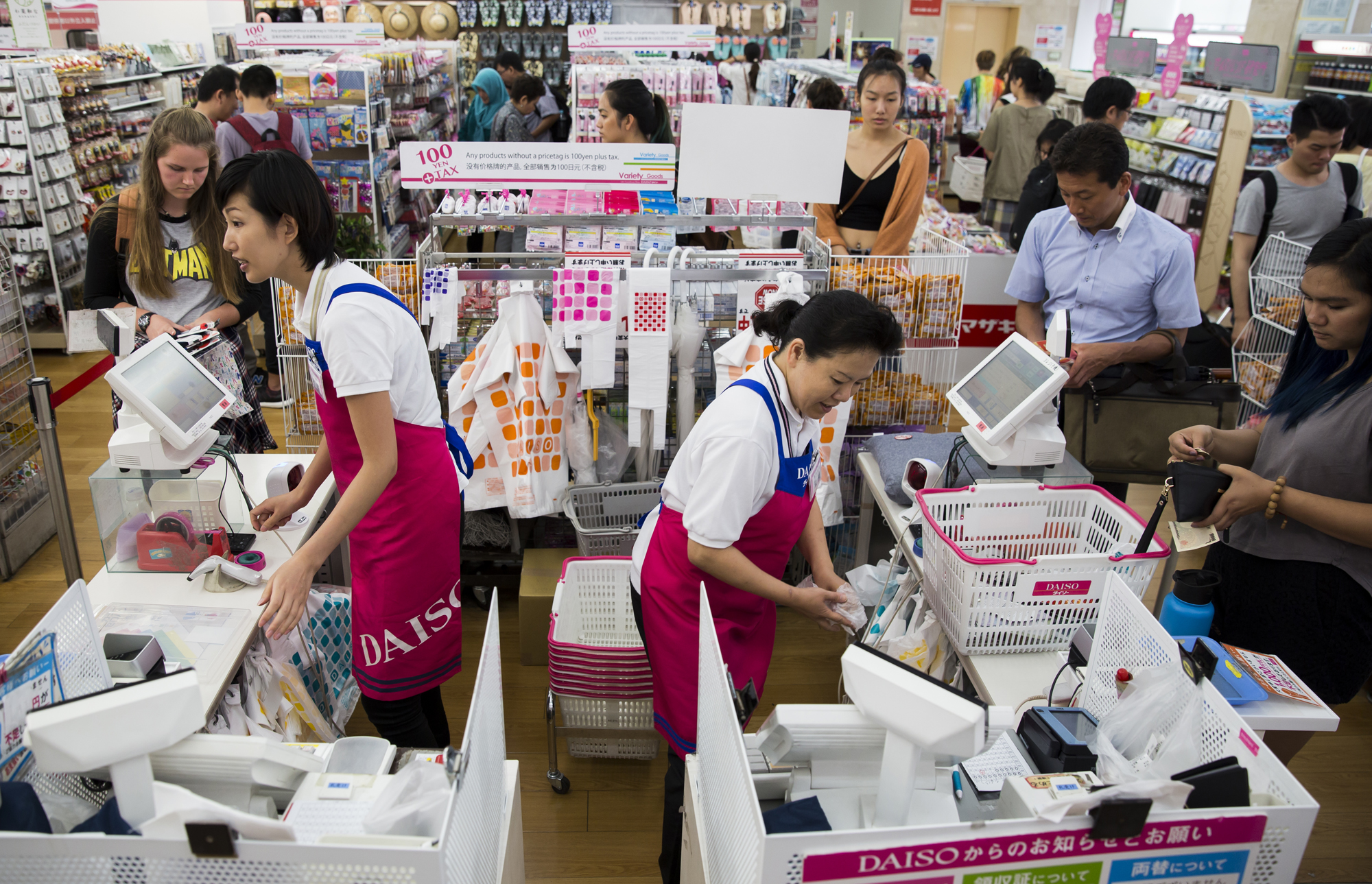 Employees work checkout counters at a Daiso store, operated by Daiso Sangyo Corp., in Tokyo in June. | BLOOMBERG