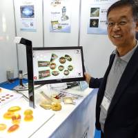 Hisashi Kanbe, CEO of a Hyogo-based company Brain Co., shows a BakeryScan image-recognition checkout system at an exhibition for automatic identification technologies at Tokyo Big Sight in Koto Ward on Sept. 15. | SHUSUKE MURAI