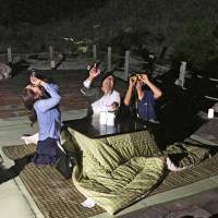 People watch the night sky sitting at a kotatsu heated table in Unzen, Nagasaki Prefecture, on Sept. 12 in a preview event for a stargazing tour that will start this Saturday. | KYODO