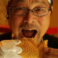 Fruit of his labor: Masao Watanabe prepares to bite into one of his apricot-filled taiyaki treats. | KIT NAGAMURA