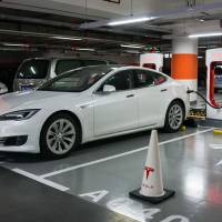 A Tesla car recharges at a Shanghai mall on Monday.  Tesla has reached an agreement with Shanghai authorities that would make it the first foreign automaker to build its own plant in China, putting the U.S. firm in the driver\'s seat in the world\'s biggest electric-vehicle market. | AFP-JIJI