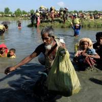 Rohingya refugees who fled from Myanmar make their way after crossing the border in Palang Khali, Bangladesh, on Oct. 16, joining hundreds of thousands of refugees already there. | REUTERS