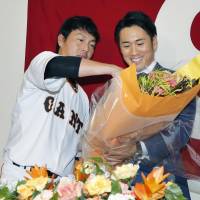 Yomiuri\'s Yasuyuki Kataoka (right) receives flowers from teammate Hisayoshi Chono during a news conference to announce his retirement on Sunday. | KYODO