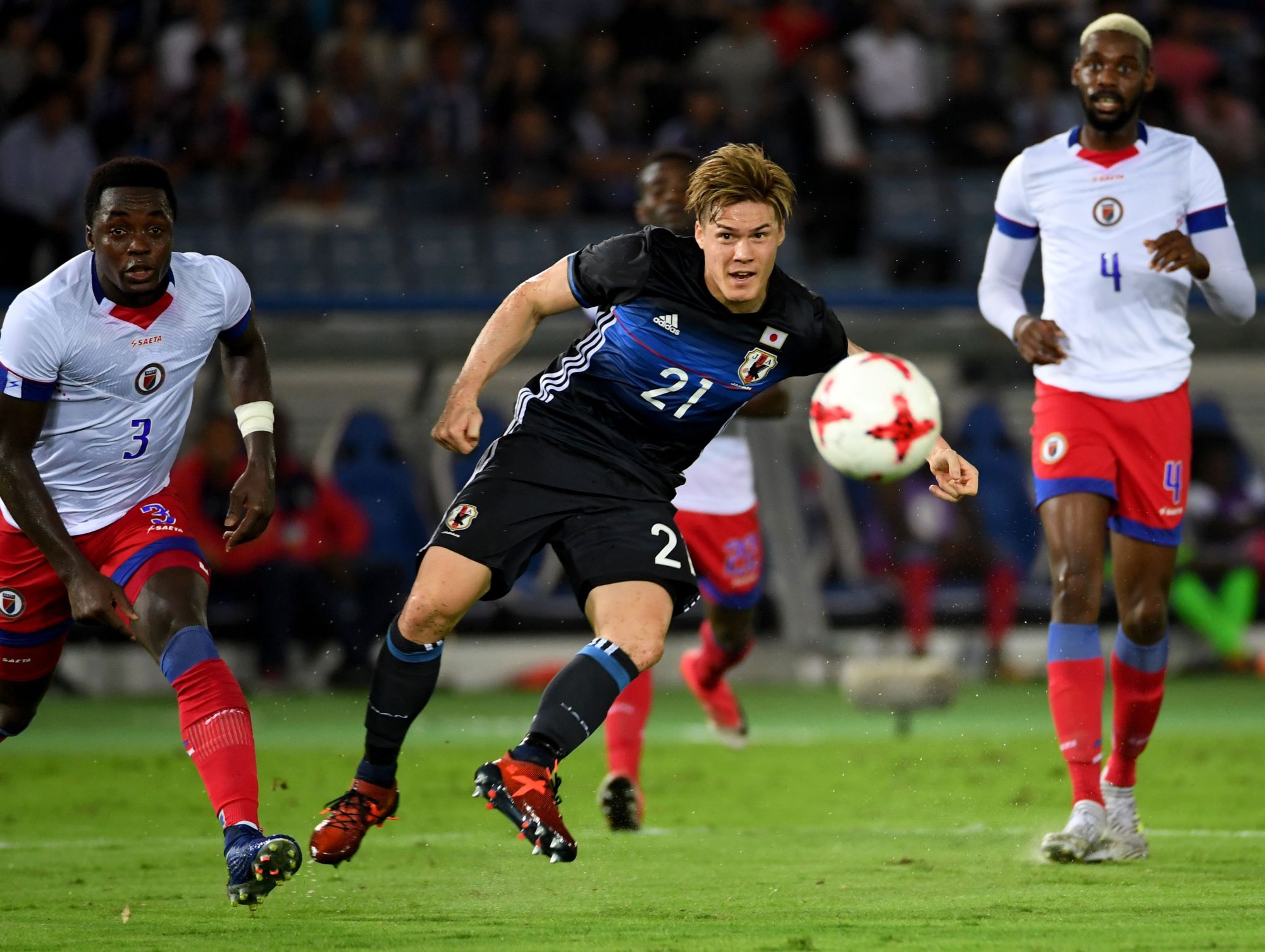 Japan's Gotoku Sakai (C) shoots the ball as Haiti's Mechack Jerome (left) and Jems Geffrard look on in an international friendly at Nissan Stadium on Tuesday night. The match ended in a 3-3 draw. | AFP-JIJI