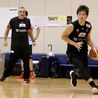 Shooting guard Naoto Tsuji moves the ball as Japan head coach Julio Lamas watches during Wednesday\'s practice for the provisional Japan men\'s national team at the National Training Center. | KAZ NAGATSUKA