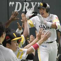 The Hawks\' Seiichi Uchikawa is congratulated by teammates after hitting a solo home run in the sixth inning. Uchikawa homered for the fourth straight game in the series. | KYODO