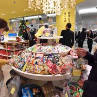 Shoppers browse the sweets at the new confectionery store Yesterday\'s tomorrow at JR Shinjuku Station in Tokyo on Friday. The store, dreamed up by Calbee Inc., opened on Saturday and stocks popular snacks and sweets from about 120 confectioners in Japan that are hard to find at supermarkets and convenience stores these days. | YOSHIAKI MIURA