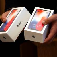 A man holds two boxes for Apple\'s new iPhone X, which went on sale Friday at the Apple Store in Regents Street in London. | REUTERS