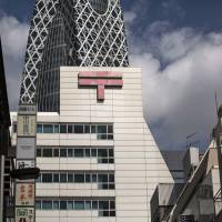 The Japanese postal mark is displayed atop Shinjuku Post Office, operated by Japan Post Holdings Co., in Tokyo on Sept. 11. ﷯Japan Post Bank Co. will invest up to &#165;500 billion﷯ in several foreign funds, according to the holding company\'s president. | BLOOMBERG