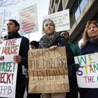 Protesters (from left) Mike Litt, lKaitlyn Vitez and Ruth Susswein gather with other members of consumer advocate groups  outside of the Consumer Financial Protection Bureau in Washington Monday during a news conference with consumer groups that oppose Mick Mulvaney being named acting director for the bureau. | AP