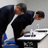 Nissan Motor Co. Chief Executive Hiroto Saikawa, flanked by Chief Competitive Officer Yasuhiro Yamauchi, bows at the start of a news conference at Nissan headquarters in Yokohama on Friday. | REUTERS