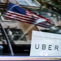 An Uber sign is seen in a car in New York in June 2015. Uber is trying to complete a deal with SoftBank Group Corp. in which the Japanese firm would invest as much as &#36;10 billion for at least 14 percent of the company. | REUTERS
