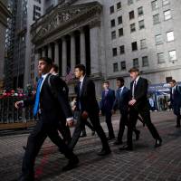 People walk along Wall Street in front of the New York Stock Exchange. | BLOOMBERG
