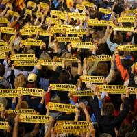 People hold banners reading, \"Free political prisoners\" outside City Hall in Barcelona, Spain, on Friday during a gathering in support of the members of the dismissed Catalan Cabinet whom a Spanish judge had ordered to be remanded in custody pending an investigation into Catalonia\'s independence push. | REUTERS
