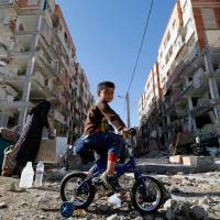A boy rides a bicycle through the rubble of damaged buildings in the town of Sarpol-e Zahab in Iran\'s western Kermanshah province, near the border with Iraq, on Tuesday, following a magnitude 7.3 earthquake that left hundreds dead and thousands homeless two days earlier. | AFP-JIJI