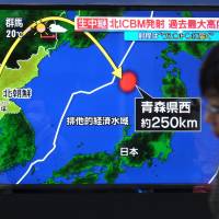 A Tokyo pedestrian passes a Wednesday morning news broadcast of North Korea\'s first missile launch since Sept. 15. | AFP-JIJI