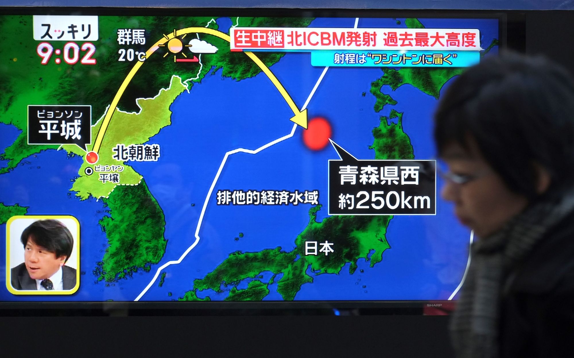 A Tokyo pedestrian passes a Wednesday morning news broadcast of North Korea's first missile launch since Sept. 15. | AFP-JIJI