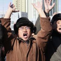 North Koreans cheer outside Pyongyang Station as they watch a news broadcast announcing the test-firing of the newly developed Hwasong-15 intercontinental ballistic missile on Wednesday. | AP