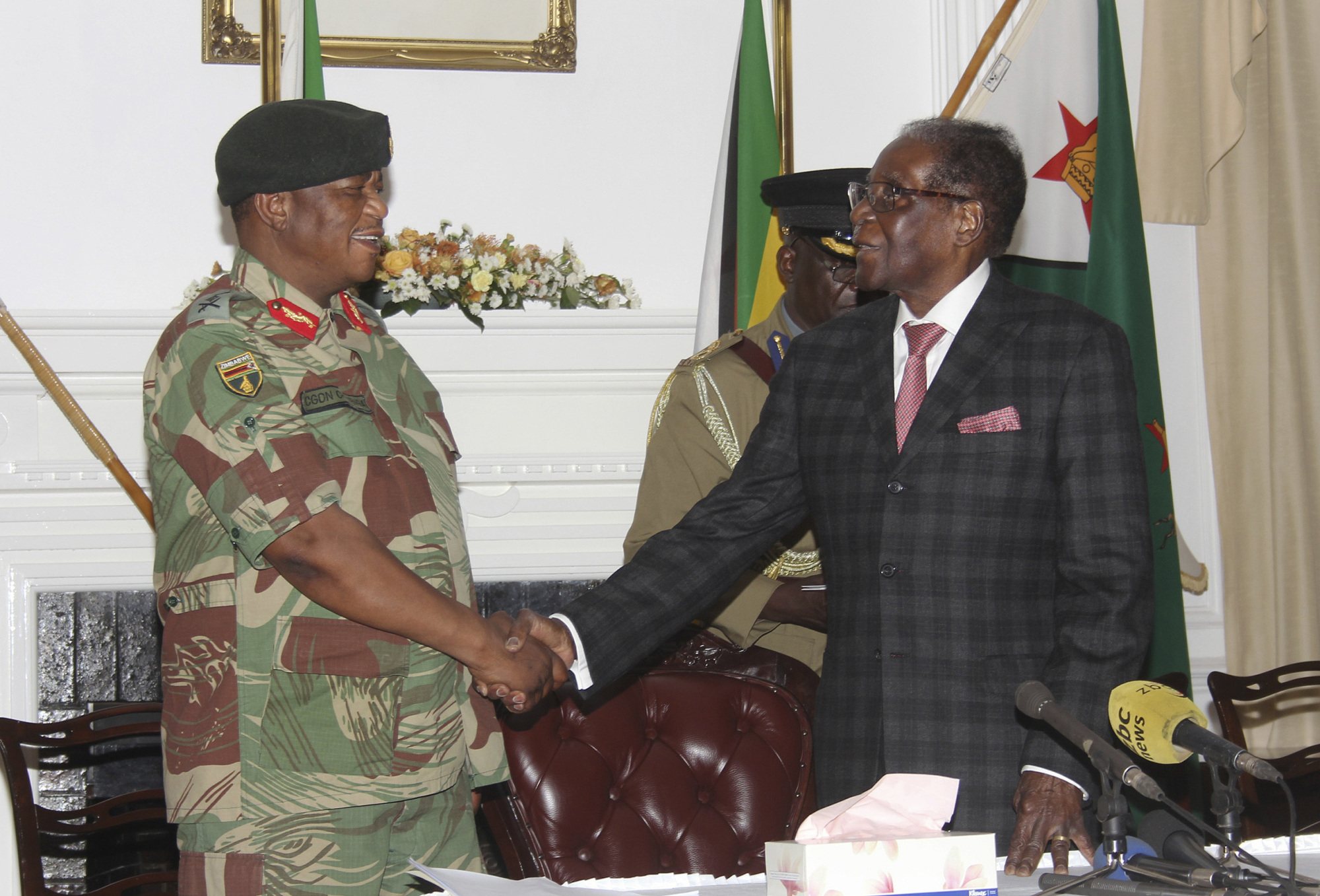 Zimbabwean President Robert Mugabe (right) shakes hands with army Gen. Constantino Chiwenga before delivering his speech during a live broadcast at State House in Harare on Sunday. | AP