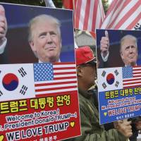 South Koreans hold placards with pictures of U.S. President Donald Trump during a rally welcoming him ahead of his visit to the country in downtown Seoul on Friday. | AP