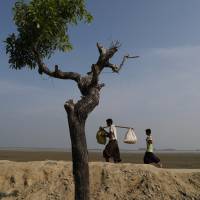 Rohingya refugee Dus Mohammed, 17, carries some of his families belongings on Thursday after crossing the Bangladesh-Myanmar border at Shah Porir Dwip near Cox\'s Bazar, Bangladesh. | REUTERS