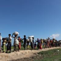Rohingya refugees walk toward a refugee camp after crossing the border in Anjuman Para near Cox\'s Bazar, Bangladesh, Sunday. | REUTERS