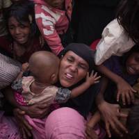 Rohingya Muslim refugees react as police and officials attempt to control a surging crowd as they wait to be called to recieve food aid of rice, water, and cooking oil in a relief center at the Kutupalong refugee camp in Cox\'s Bazar on Tuesday. Rohingya are still fleeing into Bangladesh even after an agreement was signed with Myanmar to repatriate hundreds of thousands of the Muslim minority displaced along the border, officials said on Monday. | AFP-JIJI