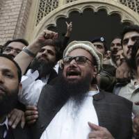 Hafiz Saeed (center) celebrates outside a court in Lahore, Pakistan, on Wednesday after it rejected the government\'s plea to extend his house arrest. | AP
