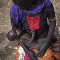 Adel Bol, 20, cradles her 10-month-old daughter Akir Mayen at a food distribution site in Malualkuel, South Sudan, on April 5. In war-torn South Sudan, 1.25 million people are facing starvation, double the number from the same time last year, according to a report by the United Nations and the government released Monday. | AP