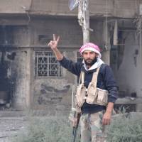 A Syrian pro-government forces member flashes the sign for victory as he patrols in the eastern city of Deir Ezzor on Saturday. Syrian and allied forces converged on holdout Islamic State group fighters in the Syrian border town of Albu Kamal, the jihadis\' very last urban bastion following a string of losses. | AFP-JIJI