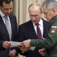 Russian President Vladimir Putin (center), Syrian leader Bashar Assad (left) and Russian Defense Minister Sergei Shoigu examine a document during their meeting in the Bocharov Ruchei residence in the Black Sea resort of Sochi, Russia, on Monday. | AP