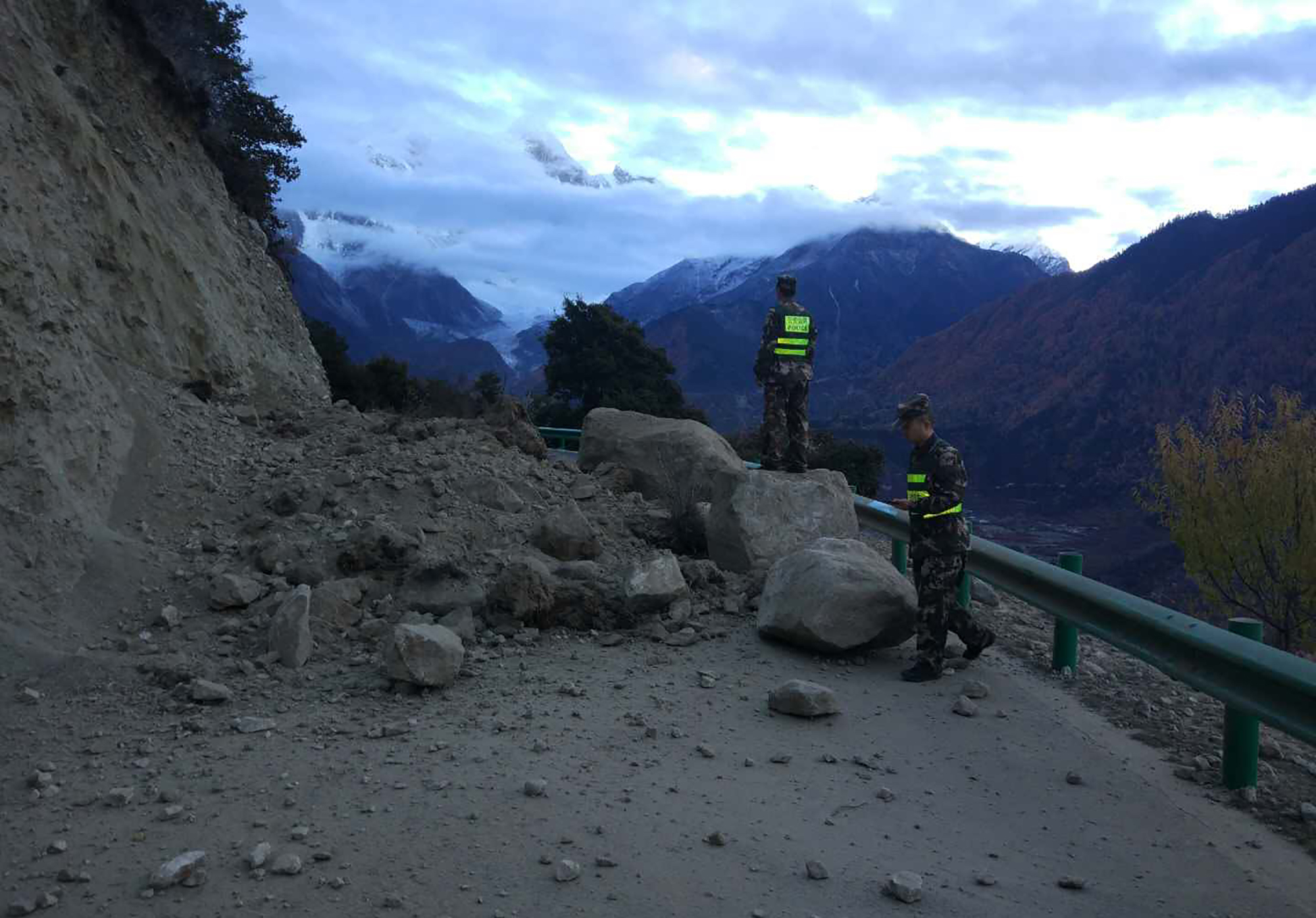 Rescuers look at a road blocked by fallen rocks near the town of Paizhen in southwestern China's Tibet Autonomous Region on Saturday after a strong earthquake shook the area. | AP