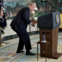 U.S. President Donald Trump looks for a water bottle while delivering remarks on his recent 11-day Asia trip in the Diplomatic Room of the White House in Washington on Wednesday. | BLOOMBERG