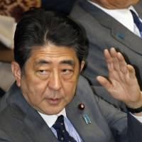 Prime Minister Shinzo Abe raises his hand during an Upper House Budget Committee session in Tokyo on Thursday. | KYODO