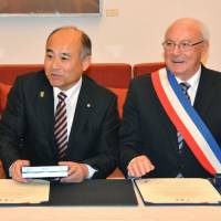 Masaomi Tokuta (left), mayor of Sagara, Kumamoto Prefecture, and Pierre Rousseau, mayor of Saint-Valentin, France, attend a signing ceremony in Paris on Friday. The two villages formed a sister-city relationship, each relying on \"love\" to boost their economy. | KYODO