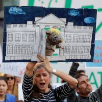 Protesters hold placards at a rally against U.S. President Donald Trump in front of Shibuya Station in west Tokyo on Sunday afternoon.  | REUTERS