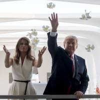 U.S. President Donald Trump and first lady Melania throw plumeria flower petals while visiting the Pearl Harbor Memorial in Honolulu on Friday. | AP