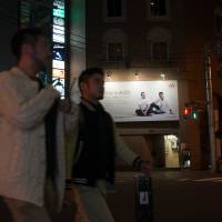 Men pass an HIV/AIDS awareness poster in Shinjuku\'s Ni-chome. | ROB GILHOOLY