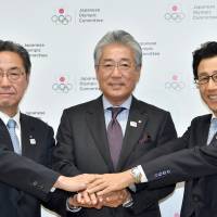 JOC President Tsunekazu Takeda (center) poses for photos with Sapporo Mayor Katsuhiro Akimoto (right) and Hokkaido Vice Governor Yoshihiro Yamaya during a news conference at Tokyo\'s Nihon Seinenkan hotel on Wednesday. | YOSHIAKI MIURA