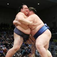 Ichiinojo (left) wraps up Kisenosato en route to a victory on Sunday at the Kyushu Grand Sumo Tournament. | KYODO