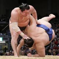Hakuho throws Ichinojo to the ground at the Kyushu Grand Sumo Tournament in Fukuoka on Tuesday. | KYODO