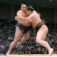 Hakuho shoves Mitakeumi out of the raised ring on Thursday at the Kyushu Grand Sumo Tournament. | KYODO