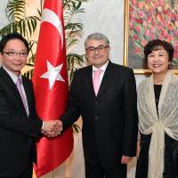 Turkish Ambassador Ahmet Bulent Meric (center) and his wife, Kumiko, welcome Keitaro Ono, parliamentary vice-minister of defense, during a reception to celebrate Turkey\'s national day at the ambassador\'s residence in Tokyo on Oct. 26. | YOSHIAKI MIURA