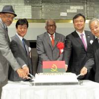 Angolan Ambassador Joao Miguel Vahekeni (center) cuts a cake  with (from left) Eritorian Ambassador Estifanos Afeworki; Takeshi Osuga, director-general of the Foreign Ministry\'s African Affairs Department; Iwao Horii, parliamentary vice-minister for foreign affairs; and Yoshifumi Okamura, ambassador extraordinary and plenipotentiary at the United Nations, during a reception to celebrate the anniversary of Angola\'s independence at Hotel New Otani on Nov. 10. | HIROKO INOUE