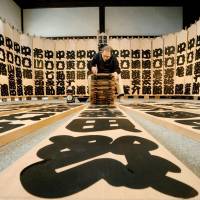 Calligrapher Masaru Inoue writes the names of kabuki actors on wooden boards on Thursday at Myodenji Temple in Kyoto prior to a year-end kabuki performance in the city. The names are written in kantei-ryu, a roundish, bold calligraphy style unique to kabuki. It leaves little empty space, symbolizing hope that the theater will be packed with audience members. | KYODO