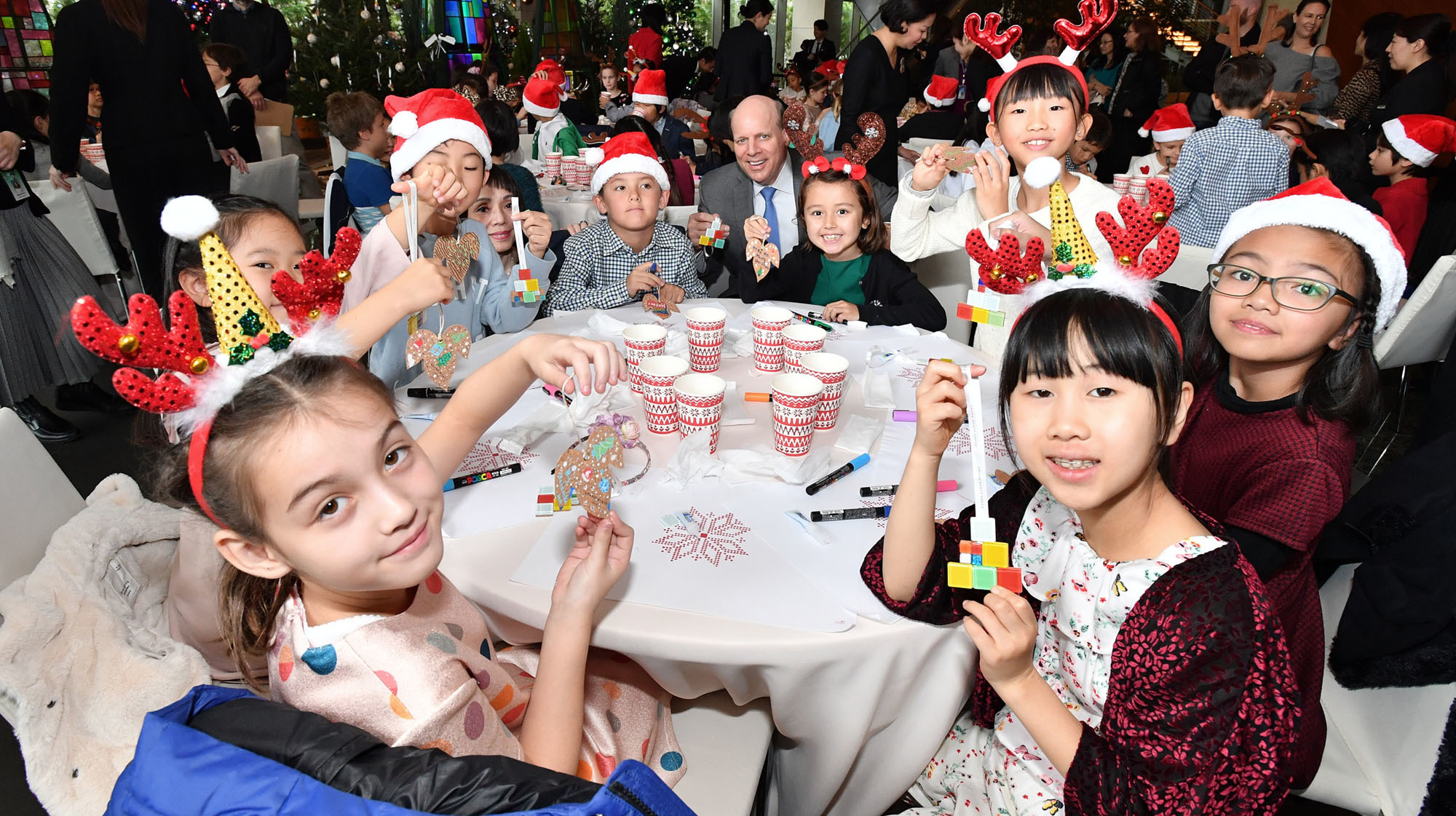Third-grade students from Nishimachi International School in Tokyo show off ornaments they made from recycled corks. The students are pictured with Grand Hyatt Tokyo General Manager Steve Dewire (center) during the opening ceremony on Tuesday of 'Colors of Hope,' a Christmas charity program to support children in the disaster-hit Tokuku region and Kumamoto Prefecture. Sixty-four students took part. | YOSHIAKI MIURA